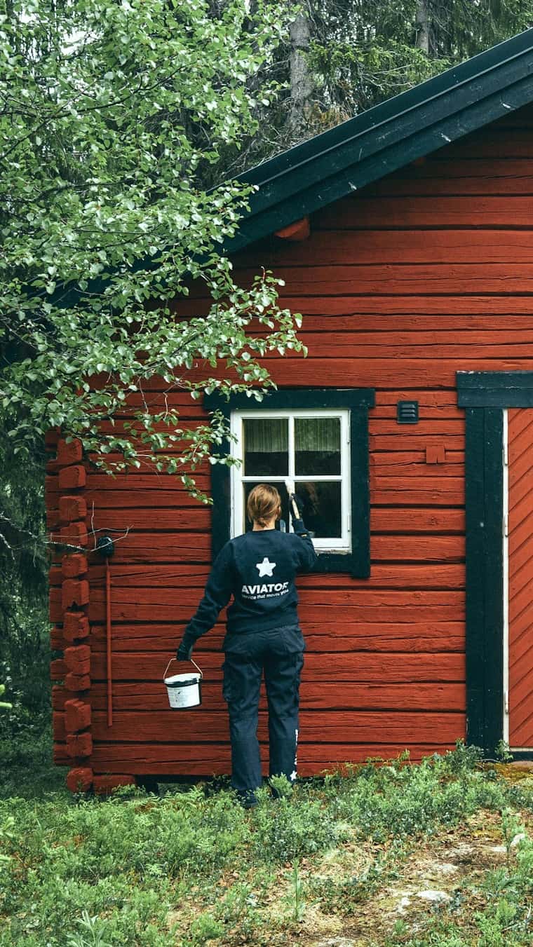 Målare vid en falu röd stuga i skogen